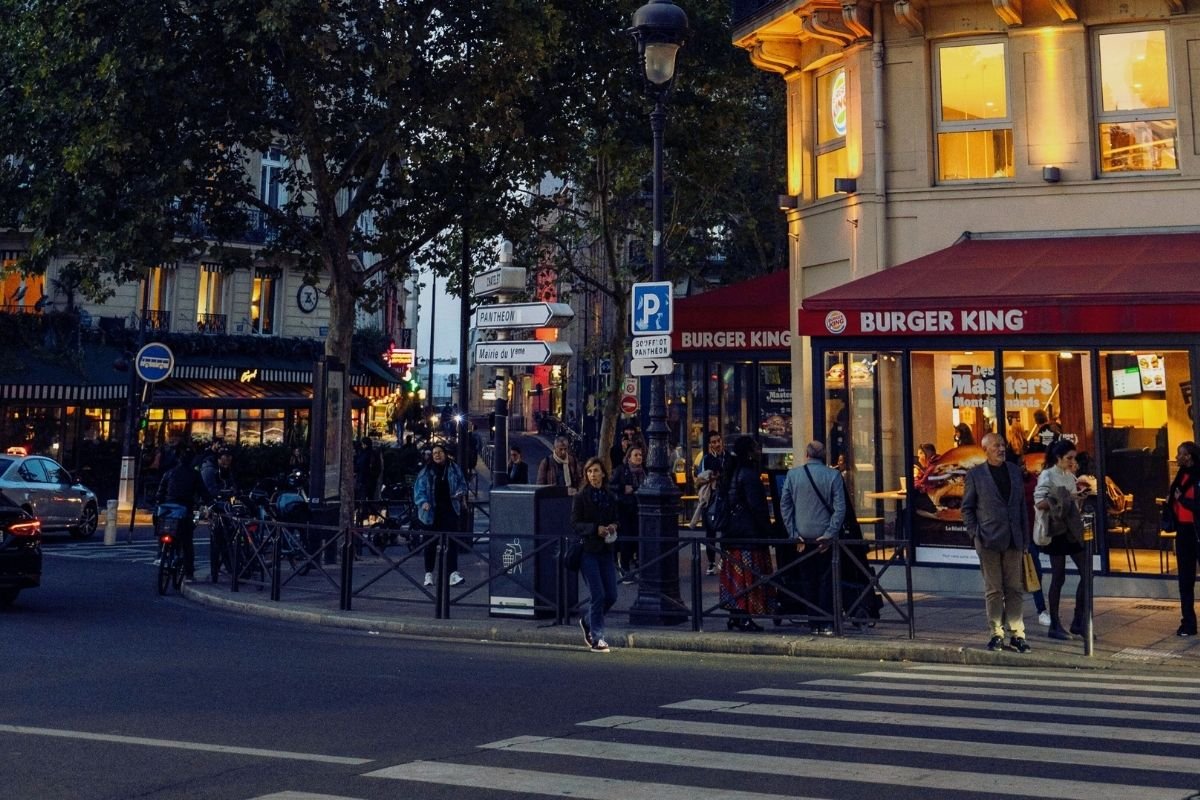 Is Paris safe at night in 2026: well-lit Paris boulevard with pedestrians walking steadily, illustrating the TripsCity visibility rule of choosing bright main streets over shortcuts