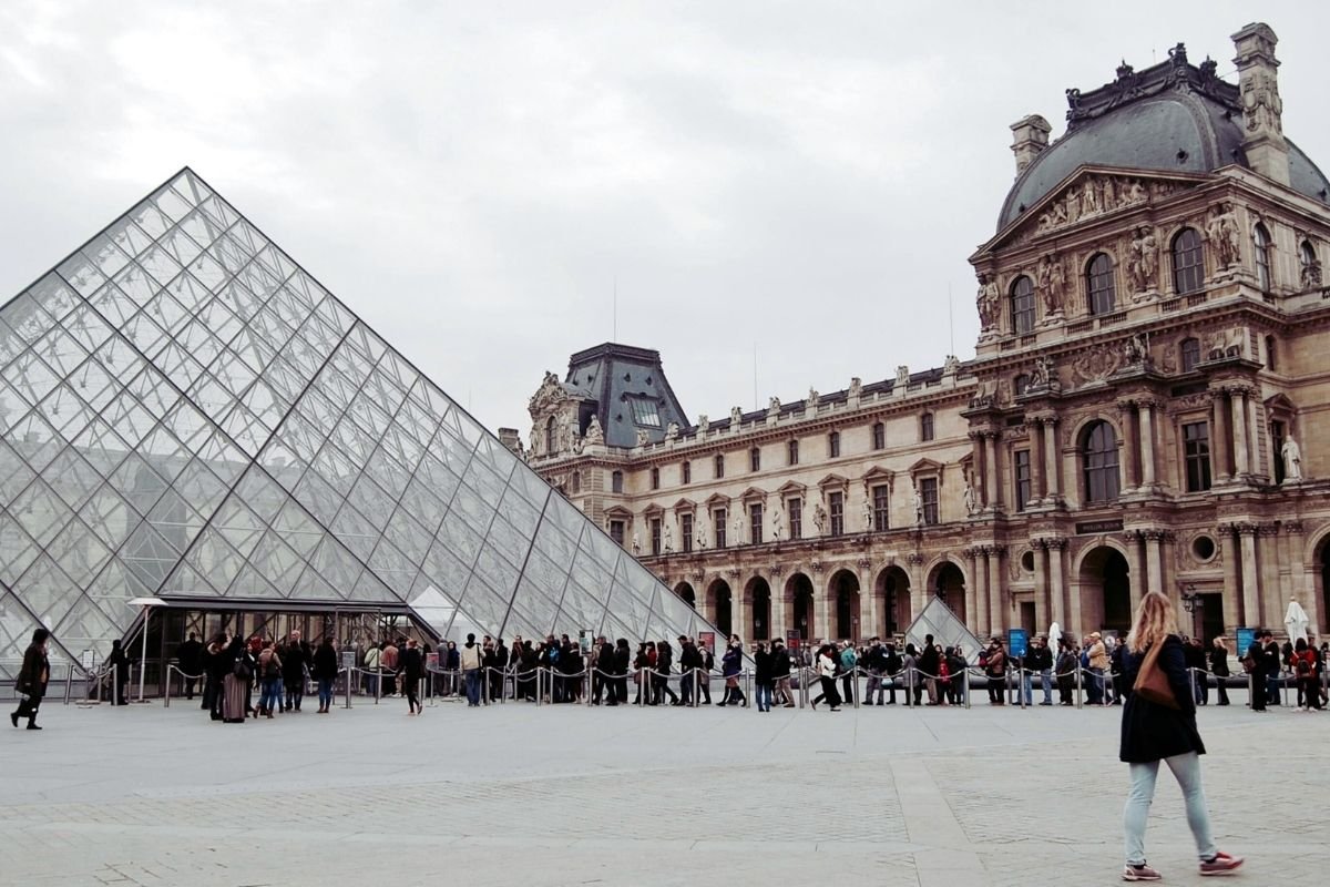 Best Paris tickets to book in advance 2026: visitors entering through a timed lane while another queue waits, showing how booked slots protect the day