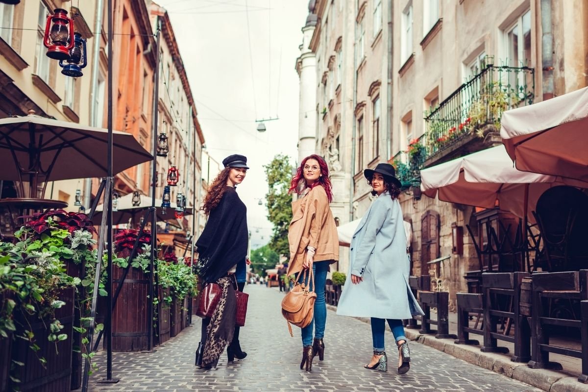 tourists walking in a calm Paris neighborhood with cafés and shops, illustrating how neighborhood-based planning reduces transport and impulse spending