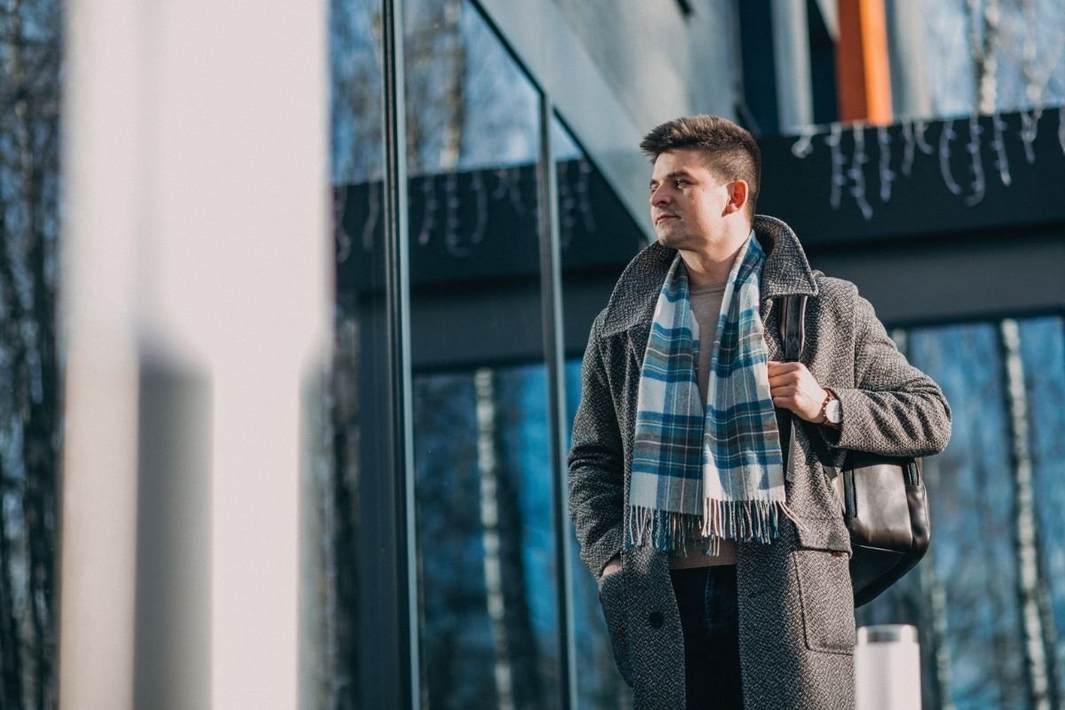 Paris packing list (2026) for winter: traveler layering a coat and scarf before leaving a hotel, showing the real pattern of cold streets and warm interiors in Paris