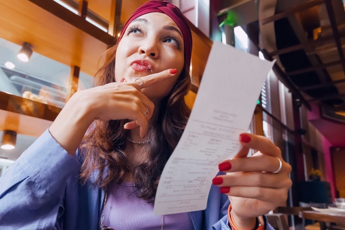Is Paris expensive for tourists in 2026: traveler looking at a café bill in Paris, illustrating how small daily costs quietly add up