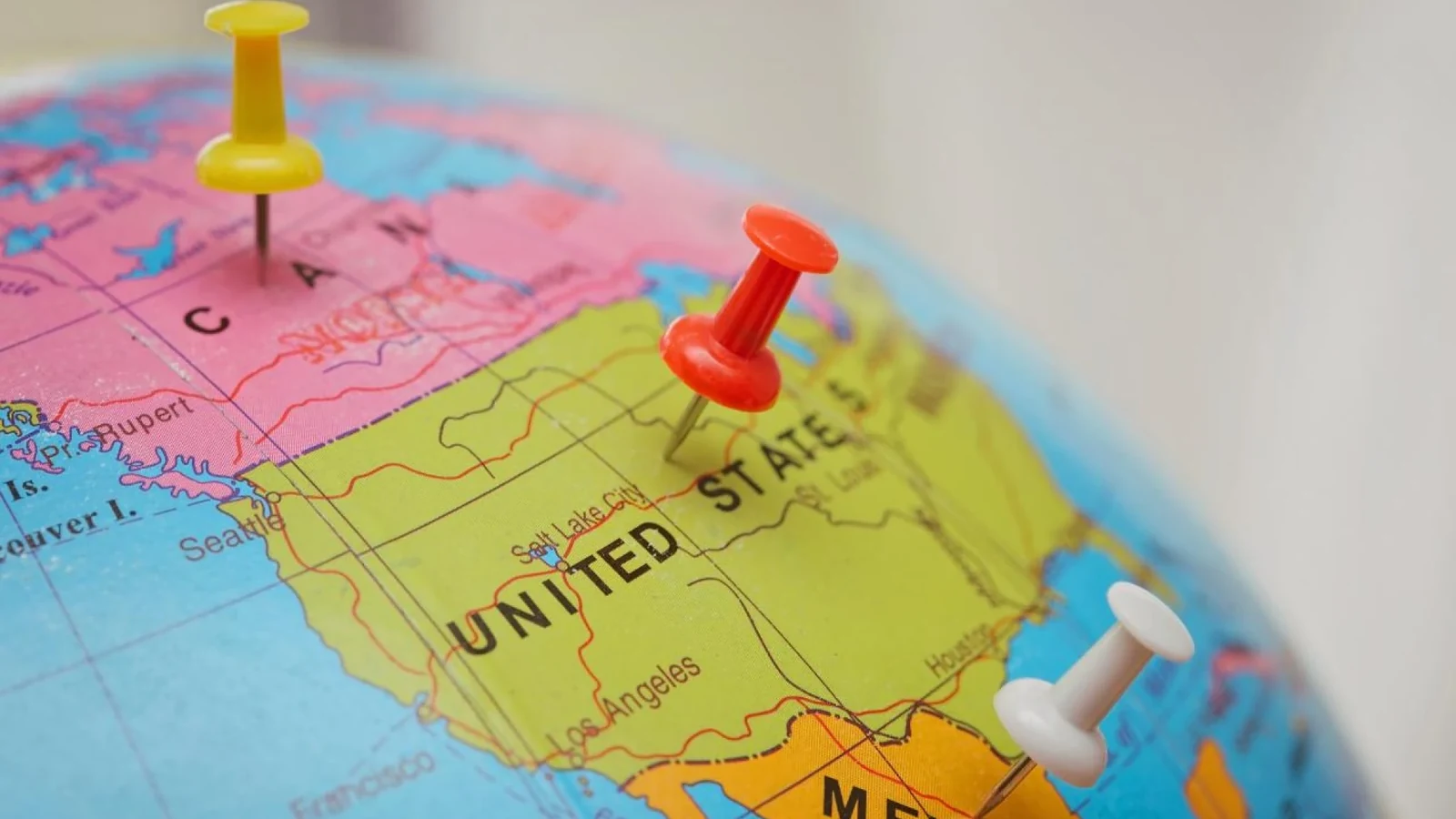 Globe with pins marking Canada, the United States, and Mexico for planning a multi-city FIFA World Cup 2026 trip.
