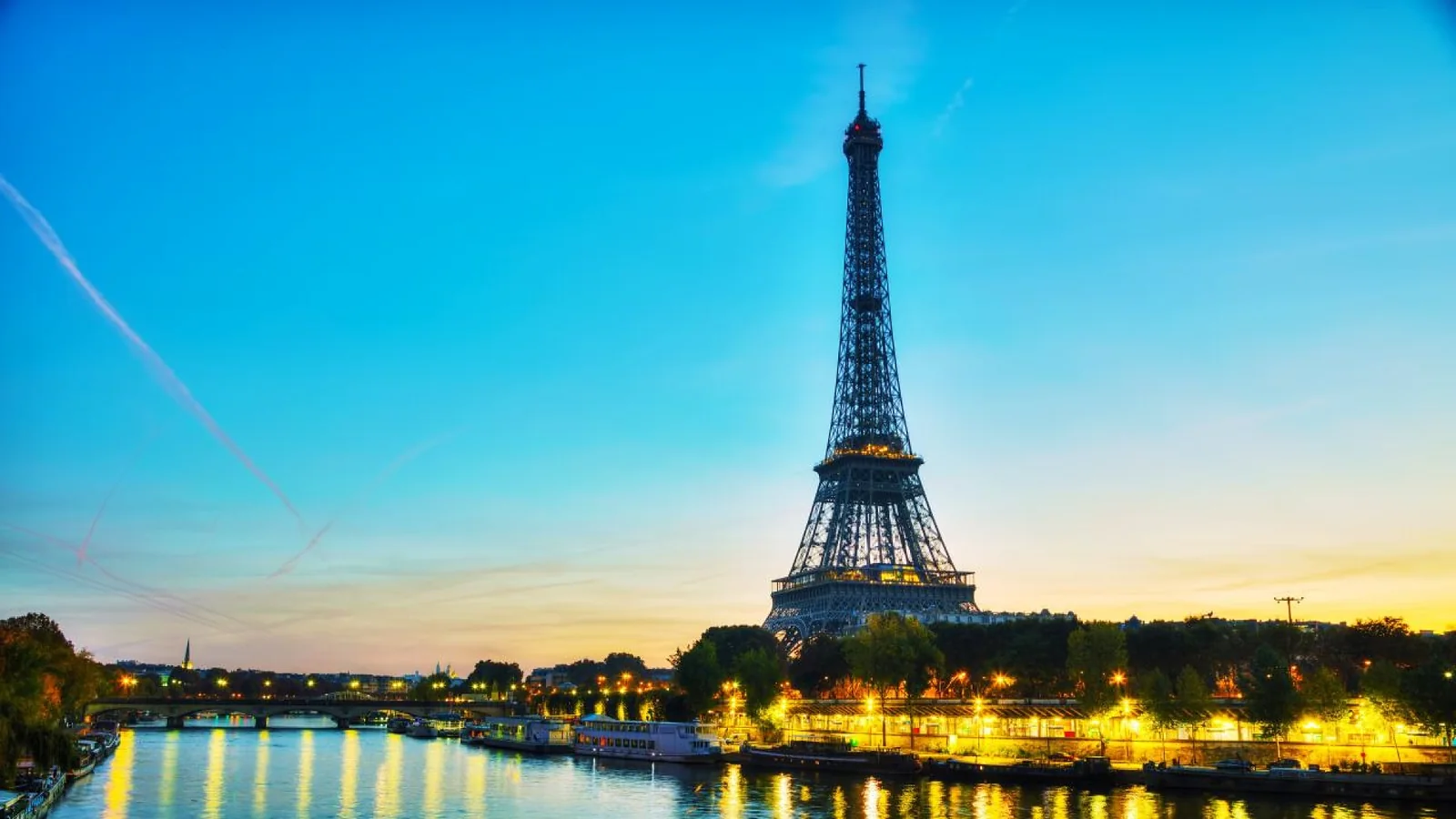 The Eiffel Tower illuminated at blue hour above the Seine River