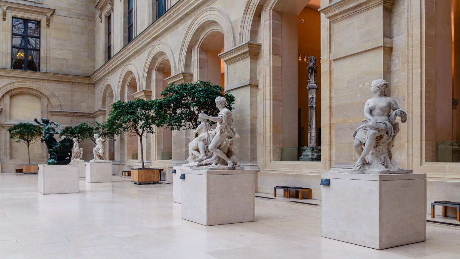 Classical marble sculptures inside a historic Paris museum gallery.