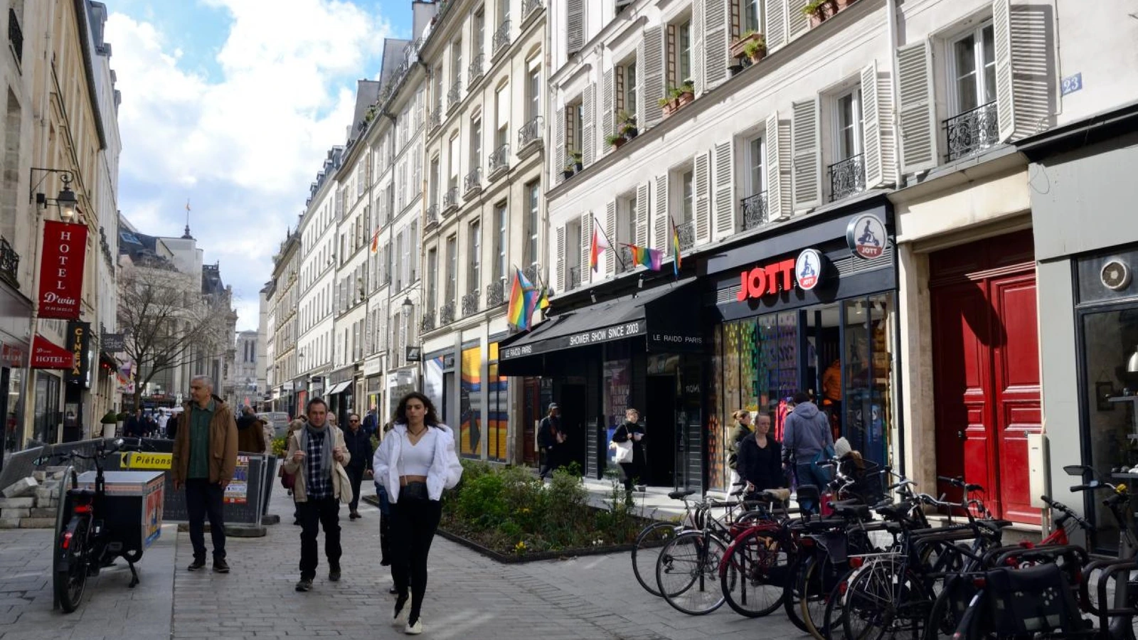 Pedestrians walking past shops and bicycles on a street in Le Marais