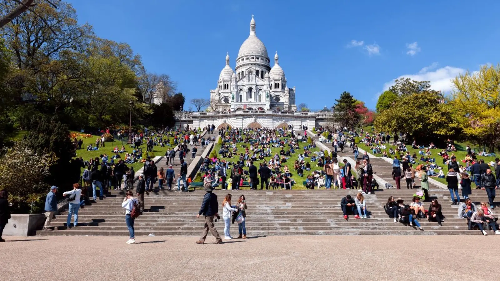 Sacré-Cœur Basilica and crowded hillside steps on a sunny day