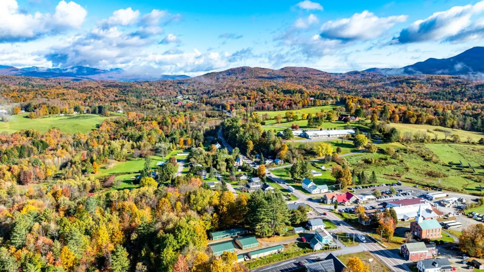 Roads wind past a village surrounded by fall foliage in Vermont.