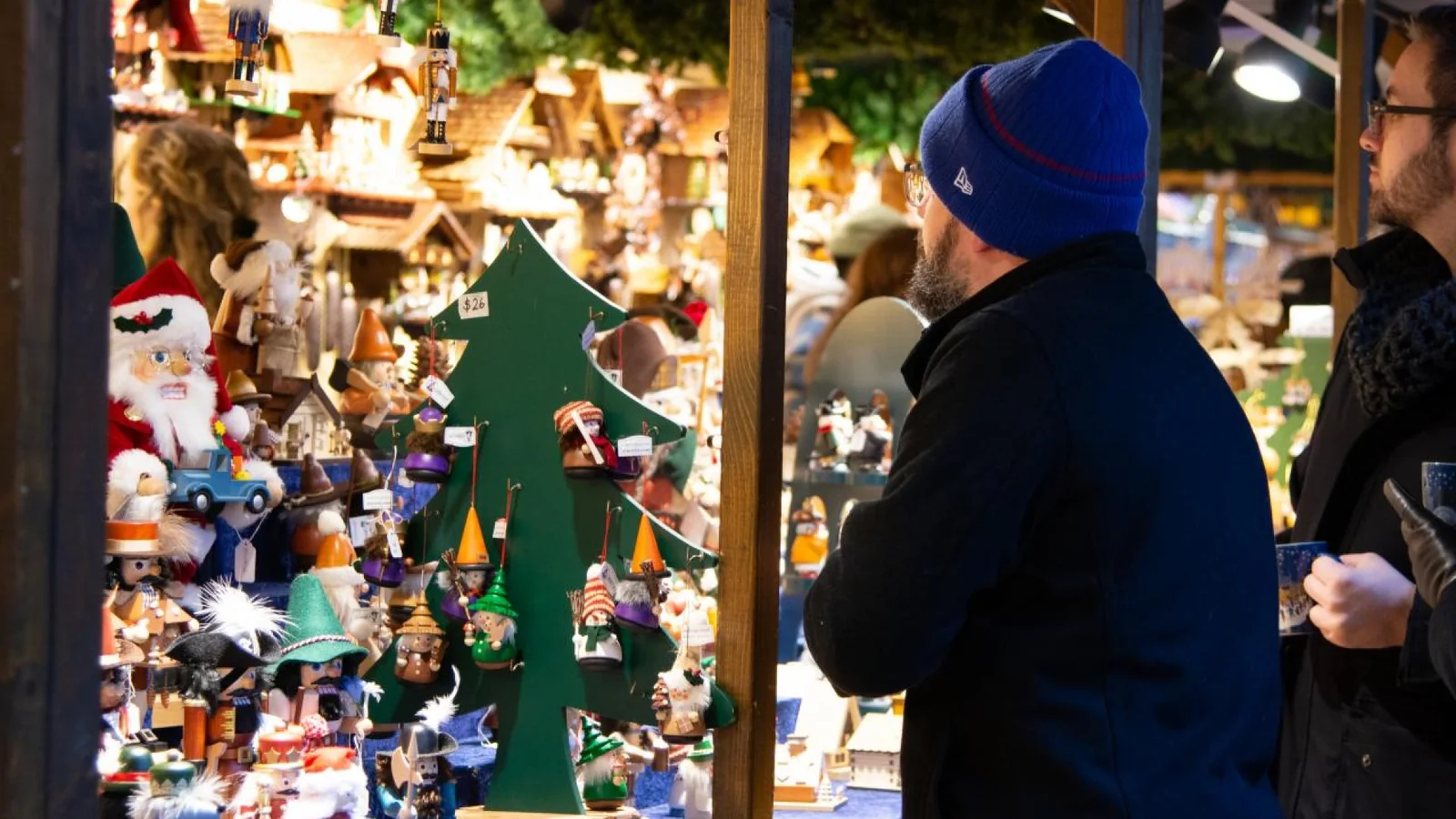 Visitors browsing handmade Christmas ornaments and gifts at a festive wooden market stall.