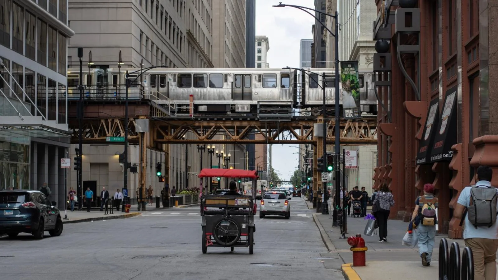 Silver CTA elevated train crossing steel tracks above a downtown Chicago street.