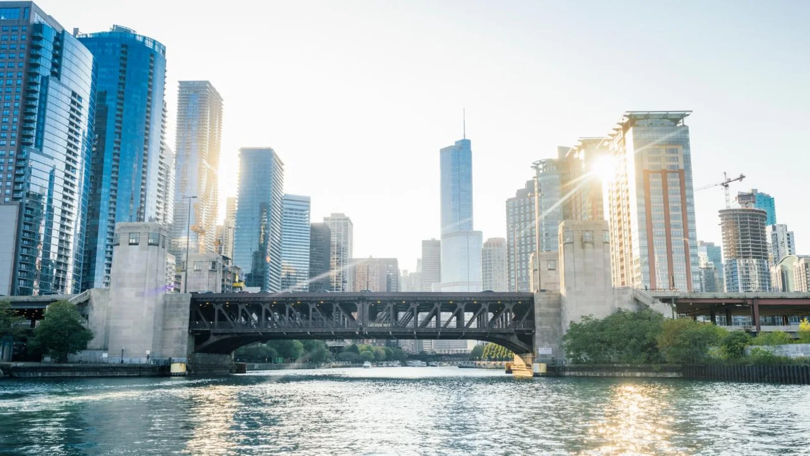 Chicago River running beneath a steel bridge with downtown skyscrapers in the background.