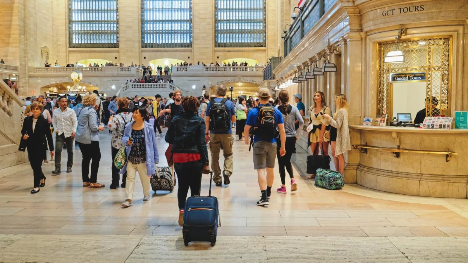 Traveler pulling a blue suitcase through Grand Central Terminal in New York
