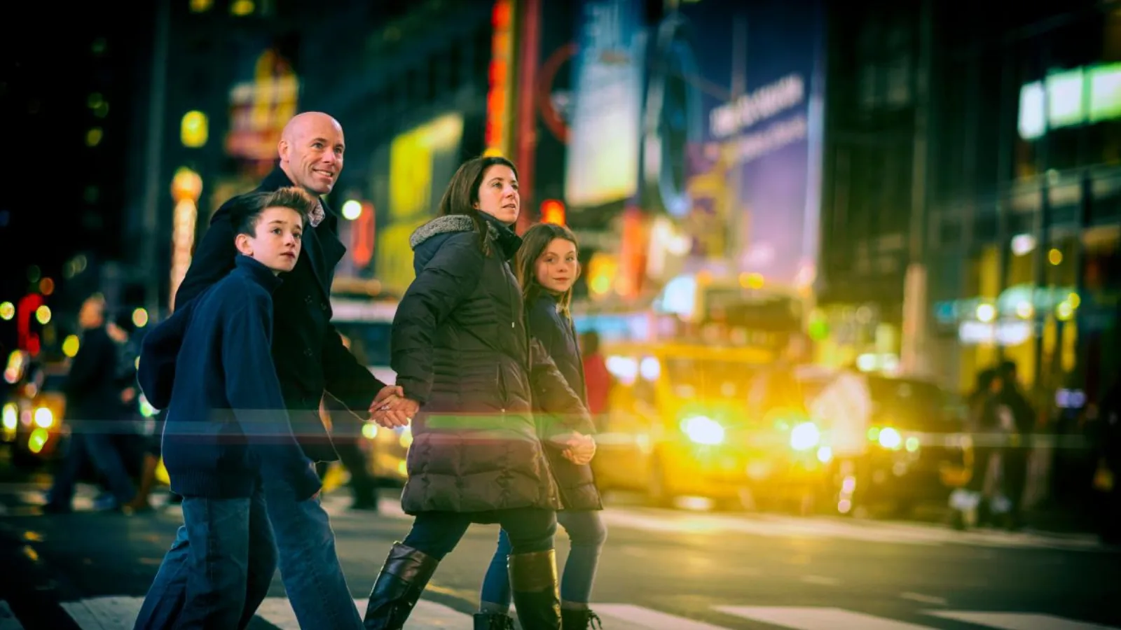 Family crossing a Times Square street in winter at night